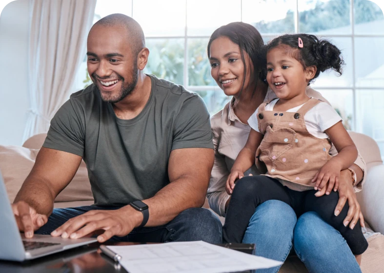 Family smiling while using a laptop together.