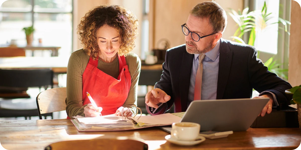 Man and woman reviewing documents in café.